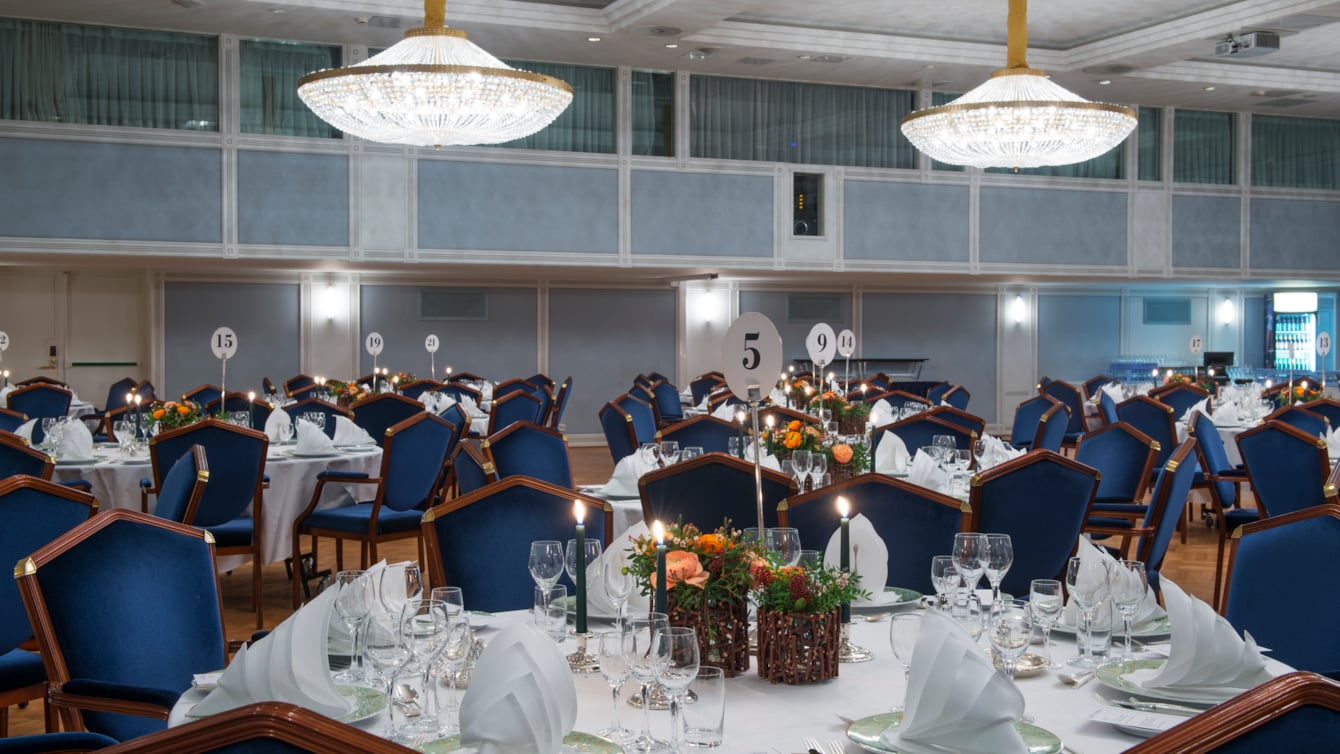 Nærbilde av oppdekket bord i Haakonsalen med brettede servietter og blomster på bordet