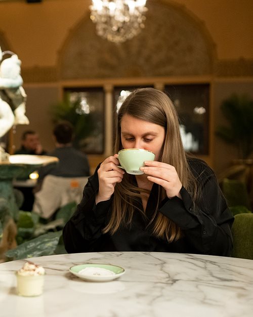 Kvinne som drikker kakao ved et bord på Hotel Bristol