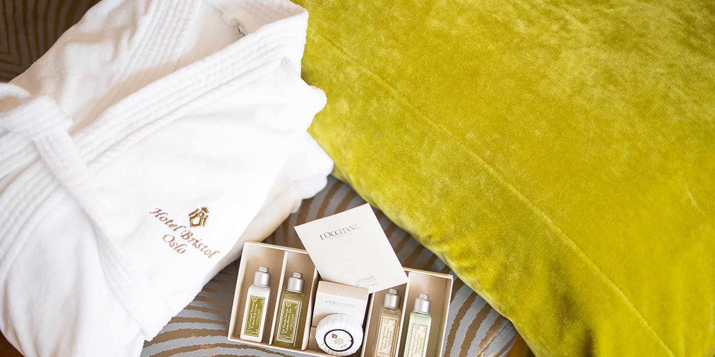 Nærbilde av badekåpe og velværeprodukter på en seng på Hotel Bristol