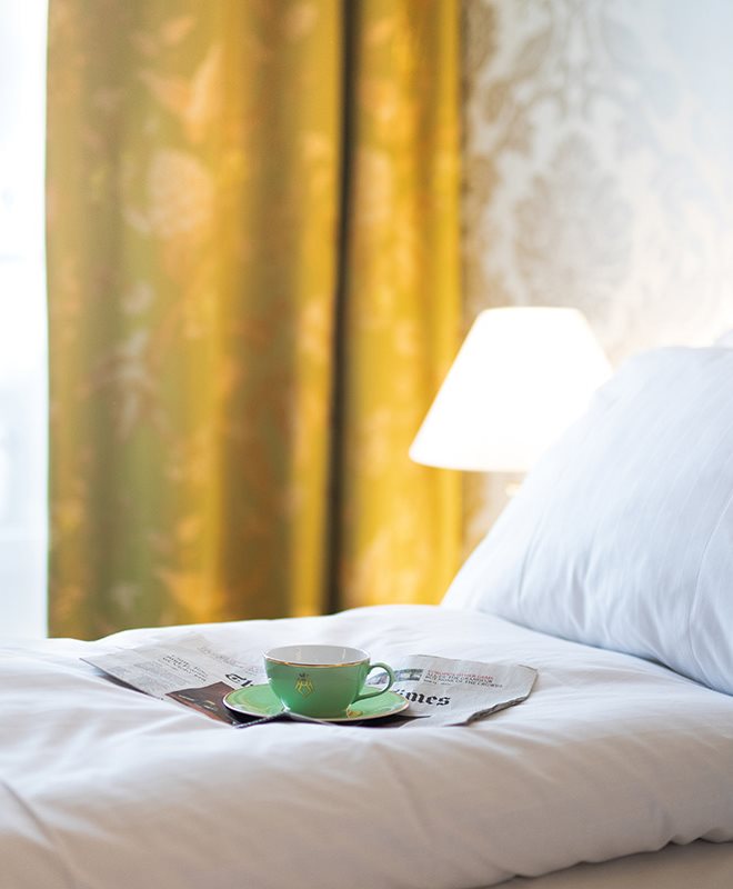 Oppredd seng med kaffekopp og avis på toppen på et hotellrom på Hotel Bristol