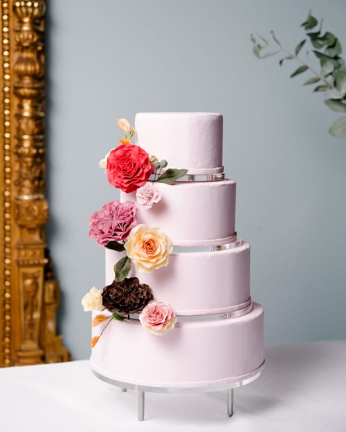 Rosa bryllupskake i fire nivåer med blomsterdekorasjon