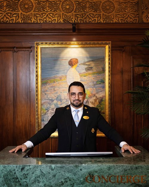 Portrett av smilende og glad concierge i uniform med turkis slips
