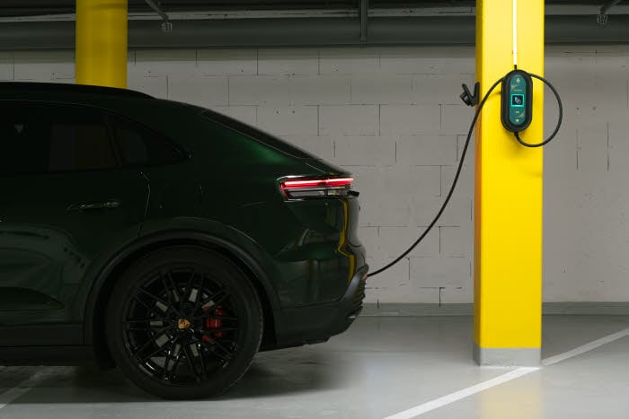 A dark electric car parked in a car park and charging.