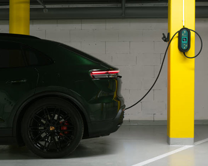 A dark electric car parked in a car park and charging.