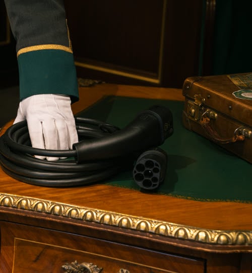 Charging cable lying on a table held by an employee wearing a uniform and white gloves.