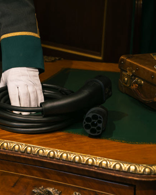 Charging cable lying on a table held by an employee wearing a uniform and white gloves.