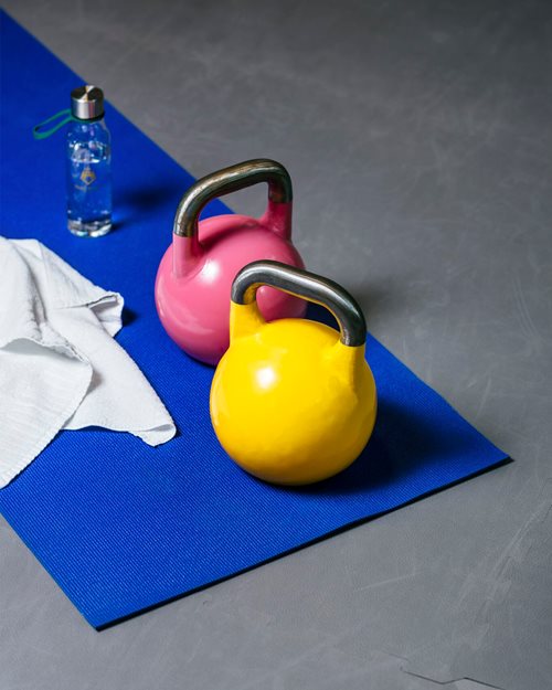 Kettlebells, et håndkle, en vannflaske på uttøyingsmatte på treningsrom