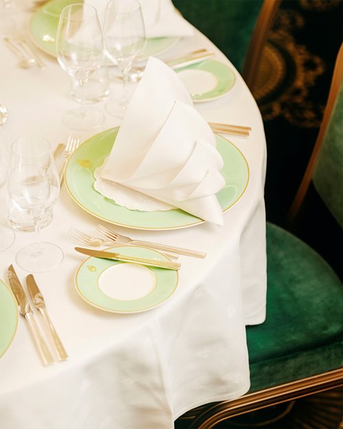 Nærbilde av oppdekket bord med hvite duker, sølvbestikk og brettet serviett