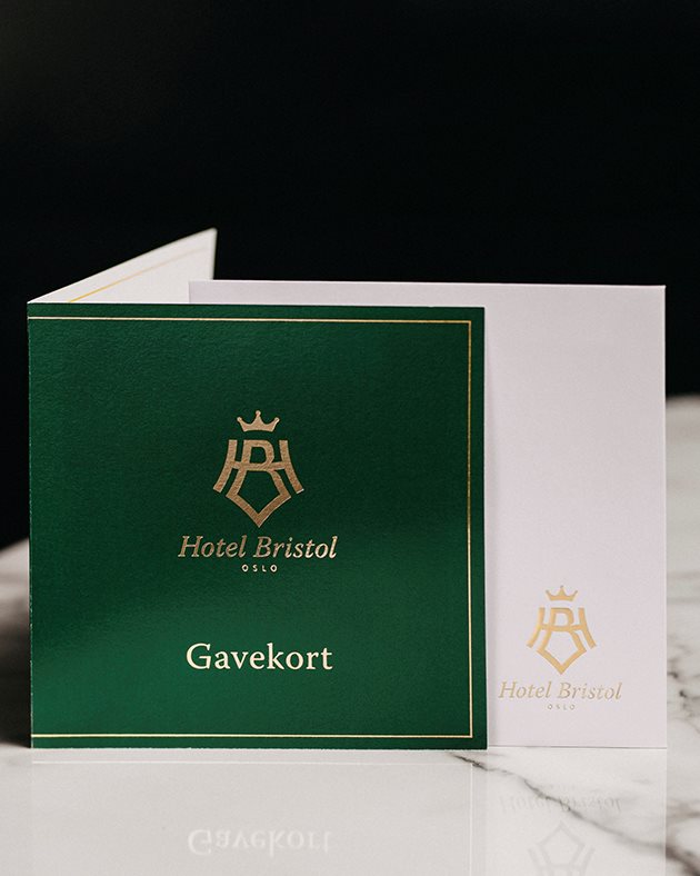 Gavekort med hotellets logo står  under juletre samme med tekopp og sandaler med hotellets logo, og gaver i gullpapir.