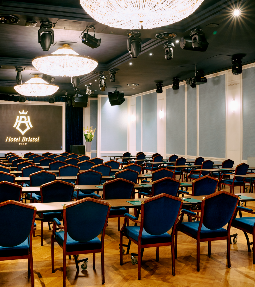 Cinema setup in Haakon Salen, with dark blue chairs and counters in each row. Light blue decorated walls and chandeliers hanging from the ceiling