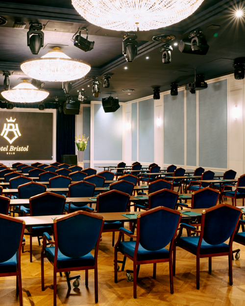 Cinema setup in Haakon Salen, with dark blue chairs and counters in each row. Light blue decorated walls and chandeliers hanging from the ceiling