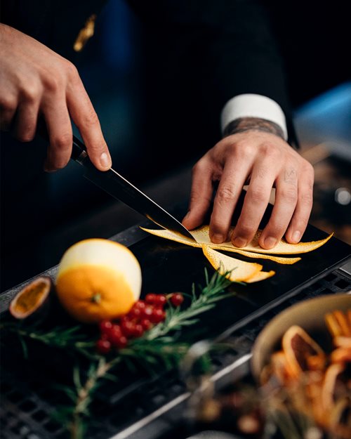 Bartender skjærer appelsinskall for ingrediens og pynt til cocktail