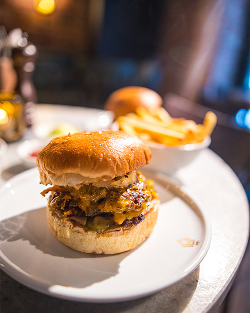 Ansatt som holder et brett med burgermåltid.