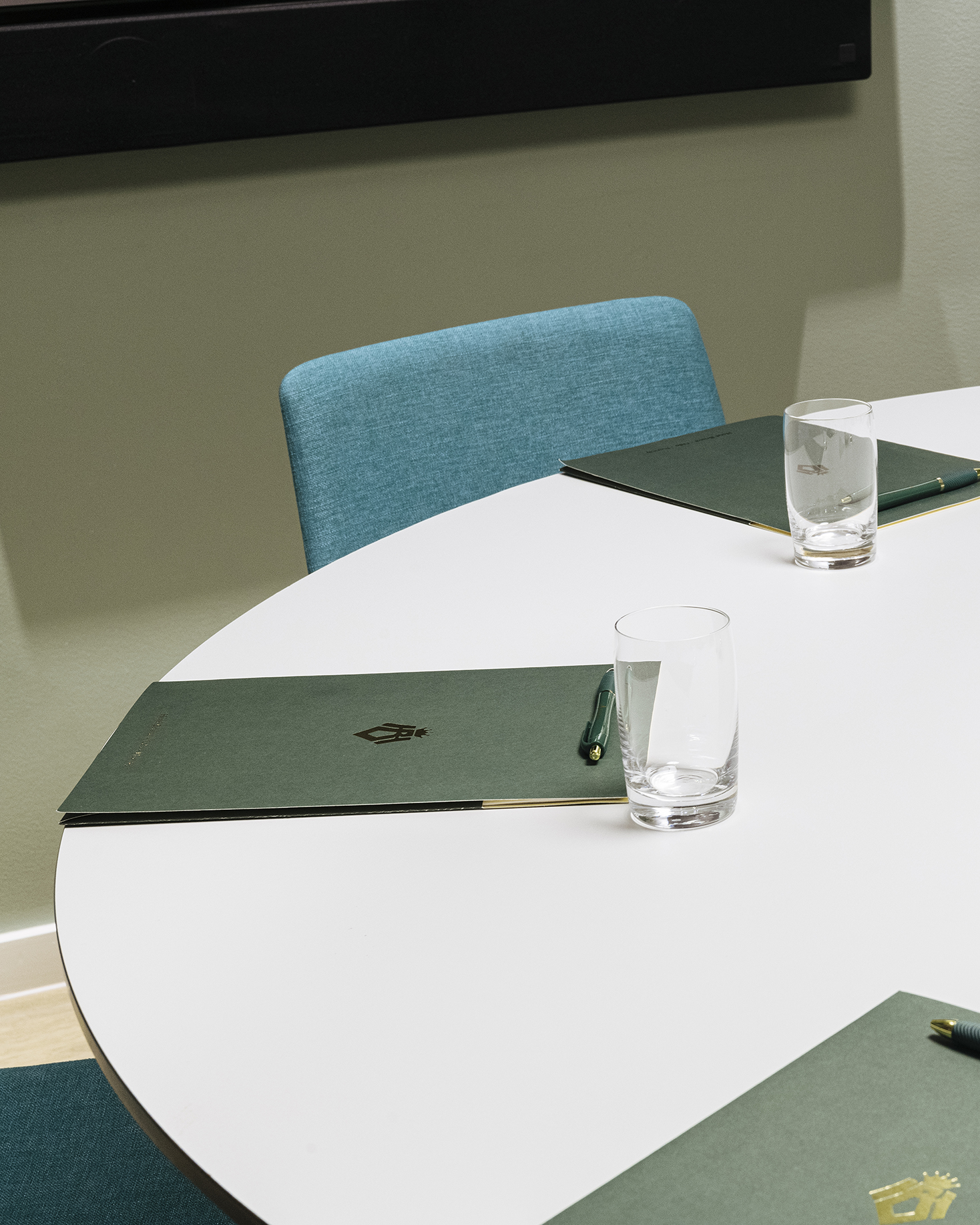 Close-up of paper bags with Bristol's logo on them, wine glasses, pen and turquoise chair in the background.