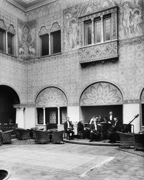 An old  photo of Den Mauriske Hall showing the high ceilings and the podium for concerts