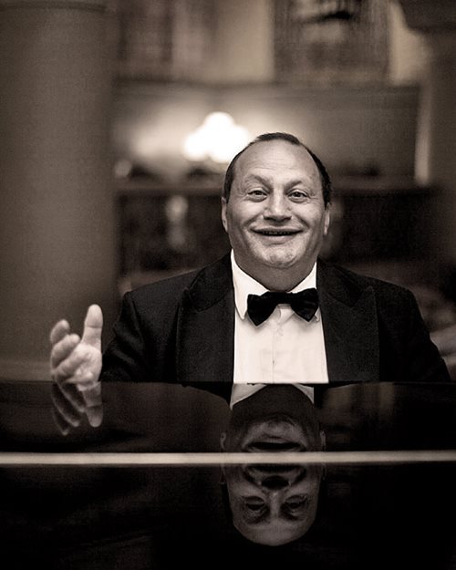 Portrettbilde av en smilende Frank Sarközi, Hotel Bristol sin huspianist. Iført smoking og butterfly.
