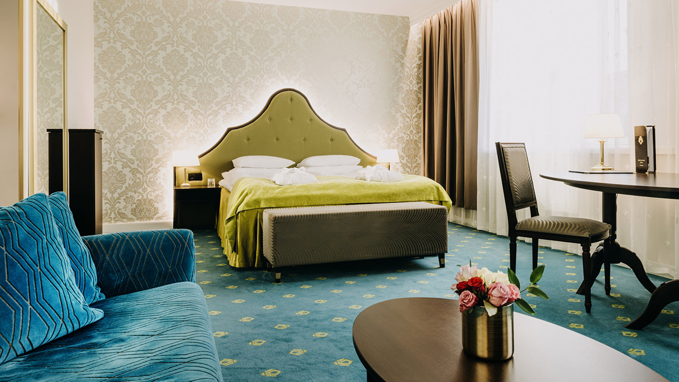 Double bed in spacious room, furnished with a small desk / dining table