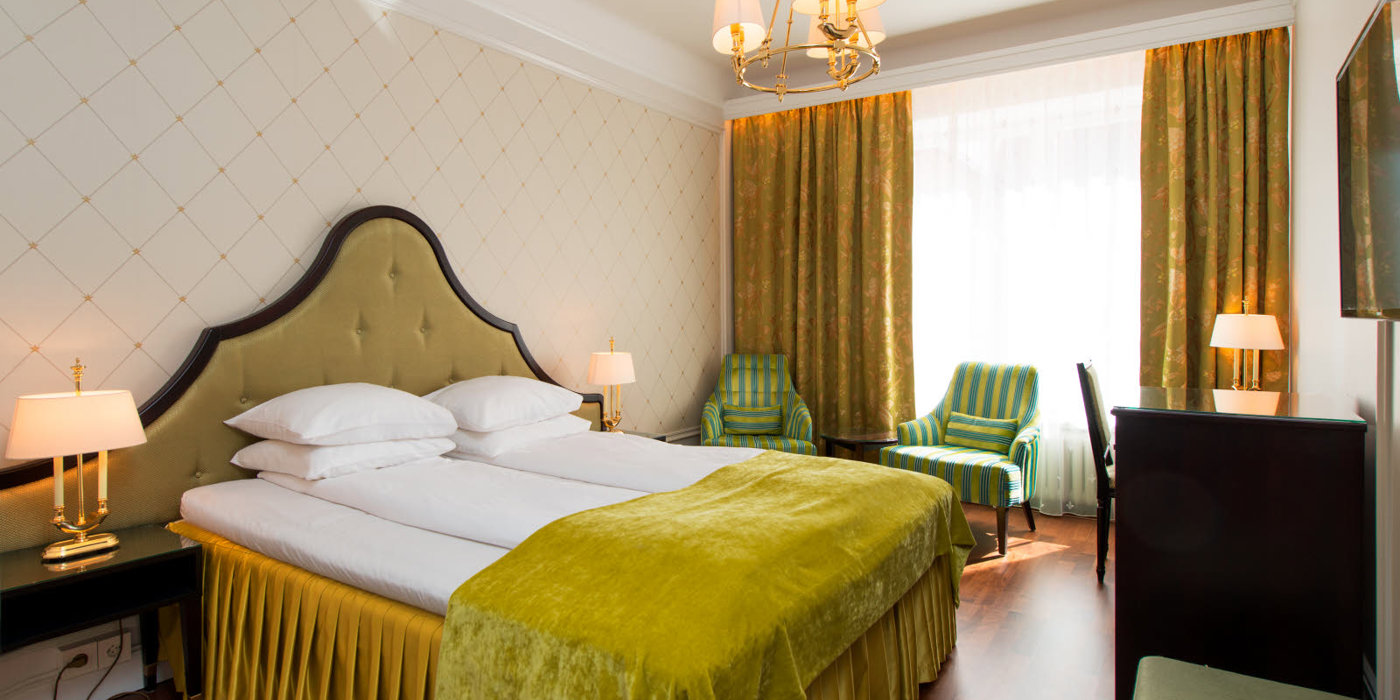 Dobbeltseng to godstoler og skrivepult på Hotel Bristol i Oslo sentrum.