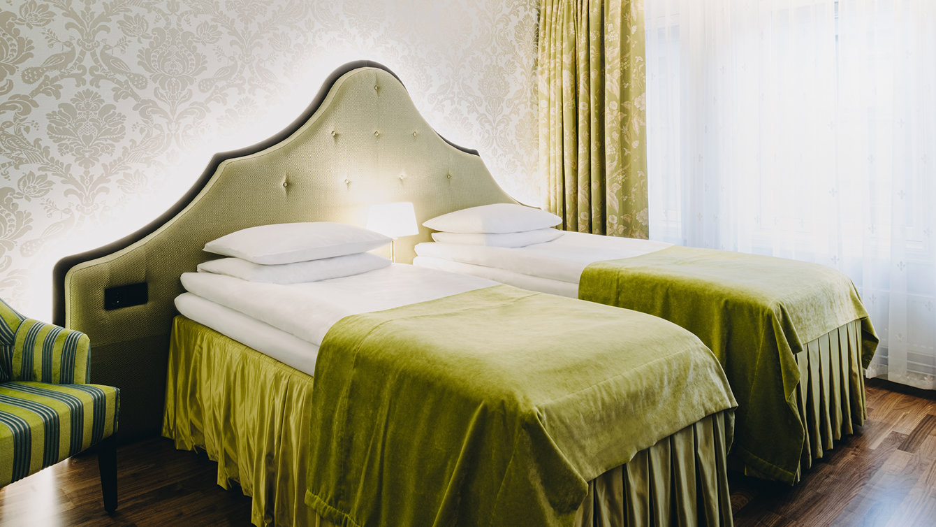A separated twin bed presented with a chair on the left hand side