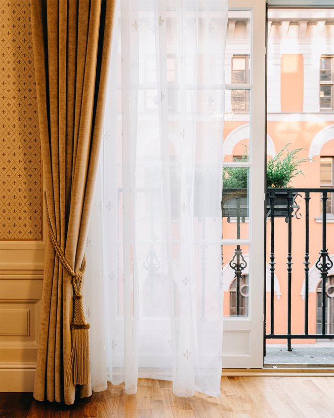 Open door to balcony in a room at Hotel Bristol. A white, light curtain hangs in front of the balcony door and a thicker curtain in front
