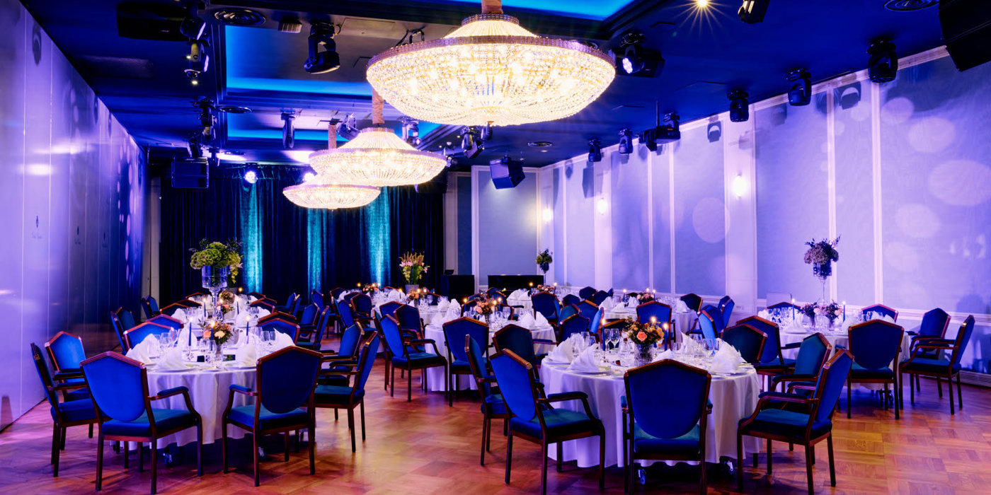 Nærbilde av oppdekket bord i Haakonsalen med brettede servietter og blomster på bordet