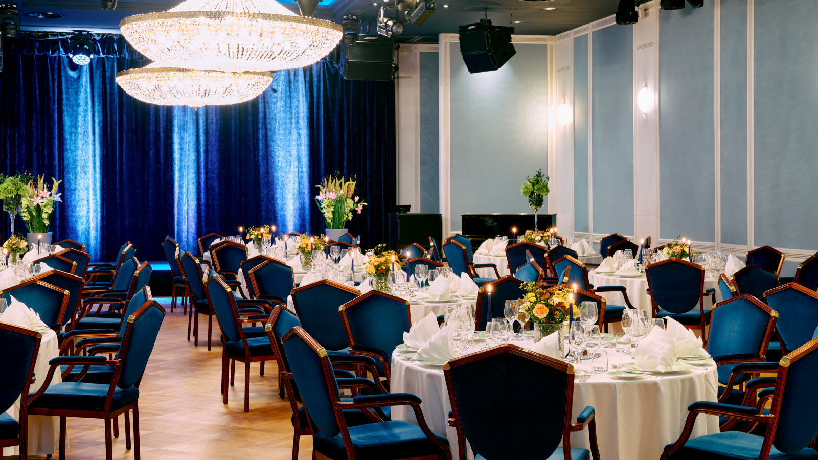 Nærbilde av oppdekket bord i Haakonsalen med brettede servietter og blomster på bordet