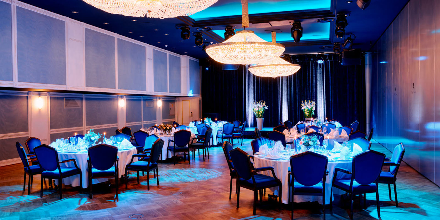 Nicely decorated table, with white linens and crystal chandeliers hanging from the ceiling