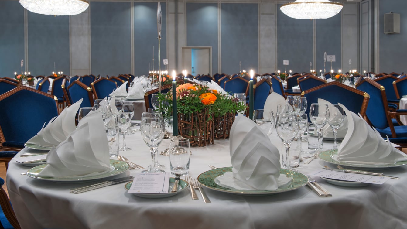 Nicely decorated table, with white linens and crystal chandeliers hanging from the ceiling  