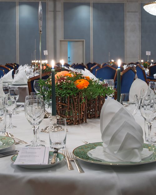 Nicely decorated table, with white linens and crystal chandeliers hanging from the ceiling  