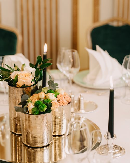 Nærbilde av dekket bord med blomsteroppsats og levende lys