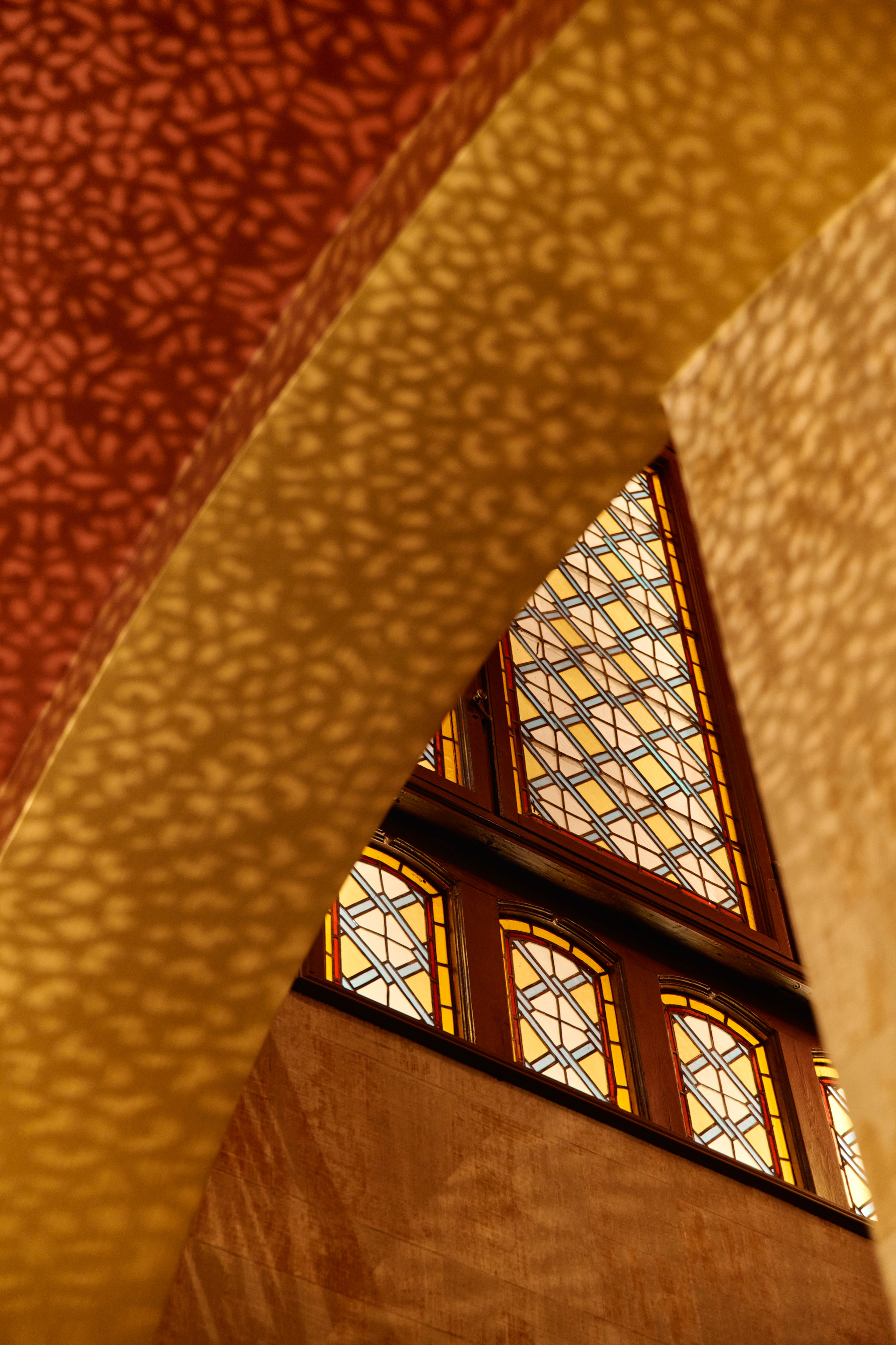 Detaljbilde av buet tak og bueformede vinduer med mønstret glass.