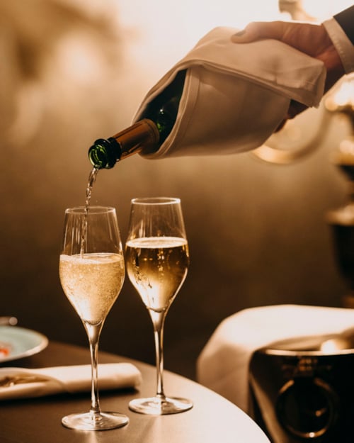 Sparkling wine is poured into two glasses