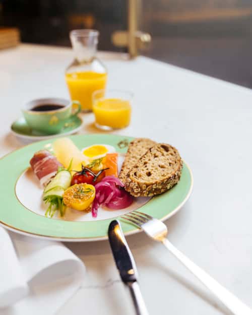 Juice og tallerken med brød, egg, laks, oster og skinker