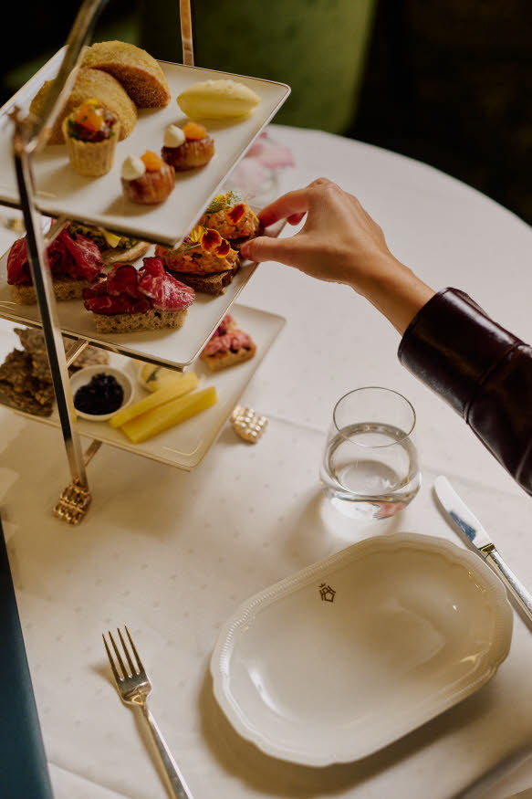 En hånd strekker seg mot et etasjefat med fingermat.