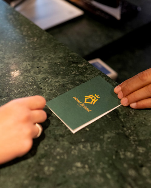 Merete og John Marius får utdelt nøkkelkort til rommet sitt på Hotel Bristol.